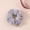 Dettaglio dell'elastico per capelli in peluche grigio ad alta elasticità su base beige - Grigio chiaro