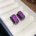 Macro shot of gun-black earrings with pink zircon stones in a velvet box - Pink