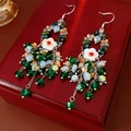 Primer plano de pendientes boho de cuentas con flores sobre una caja de regalo de madera roja - Estilo de Borla con Gancho para la Oreja / Plata/Verde