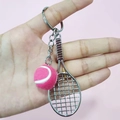Hand holding a creative tennis racket keychain with pink fuzzy ball on pink background - 2cm Ball / Pink