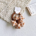 Detailed close-up of a polka dot fabric flower hair tie with a soft plush center - Coffee Polka Dot