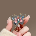 Macro shot of butterfly brooch with gold frame, blue enamel and hanging pearls - 435# Butterfly