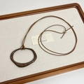 Détail du collier à cordon marron réglable avec pendentif géométrique sur plateau en lin - Marron