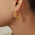 Eleganti orecchini a cerchio a C dorati con design intrecciato su modella femminile - Oro