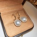 Primer plano de elegantes pendientes de perlas blancas en forma de gota dorados - Ganchos de oreja de perlas blancas