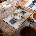 Detail of woven linen placemat with fringe on a rustic wooden table setting - Grey and White