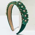 Detailed macro of baroque headband with green crystals and pearls on green velvet fabric - Green