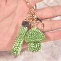 Close-up of a green rhinestone mushroom keychain with gold hardware held in hand - Green