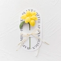 Close-up of handmade yellow knitted tulip with green leaf and Love Is Eternal ribbon - Blooming Tulip - Yellow