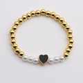 Bracciale di perline dorate e perle bianche con ciondolo a cuore nero su sfondo bianco - Nero