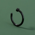 Makro-Detail eines schwarzen polierten U-Nasenrings aus Edelstahl auf grünem Grund - Schwarz Kreis