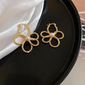 Detailed shot of hollow metal flower earrings with white pearls on black silk display - Ear Buckle / Gold