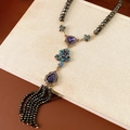 Close-up of vintage snake chain necklace with purple glass beads and black tassel on a book - Vintage Tassel Necklace (Necklace-Purple-Blue)