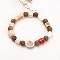 Armband aus Keramik und Holzperlen mit Blumenblättern auf Leinenhintergrund - 30 Holzperlen Serie F