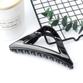 Minimalist black triangular hair claw clip displayed in a lifestyle setting - Glossy Black