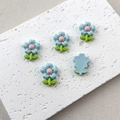 Macro shot of five blue resin flower charms for DIY hair clips on a white stone base - 5# Blue Flower