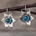 Gros plan de boucles d'oreilles vintage en argent avec gemme bleue sur une branche - Boucles d'oreilles / Bleu