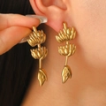 Détail de longues boucles d'oreilles pendantes bananes dorées portées par un mannequin - Forme de Banane