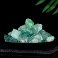 Pile of natural green fluorite rough stones on a dark tray with green leaves background - Green Crystal Stone (200g)