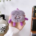 Detail of purple plush cartoon case for AirPods Pro held in hand against home background - Purple Plush Monster Smiling Expression / AirPods 1/2 Gen
