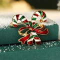 Christmas brooch with crossed candy canes and a red bow on a snowy green background - Christmas Cane Bow
