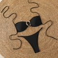 Flat lay of black bandeau bikini set with gold metal ring detail on a straw mat - S / Black