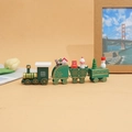 Green wooden Christmas train detail featuring bear, snowman and tree on beige background - Green