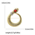 Spilla a serpente vintage dorata con occhio di gemma rossa e strass su sfondo bianco - Serpente Oro/Gemma Rossa