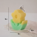 Yellow flower shaped scented candle with green base and paper tag in cozy setting - Yellow Flower Light Green Leaf