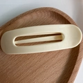 Minimalist large matte cream hair clip in a modern oval hollow design on wood tray - Cream White
