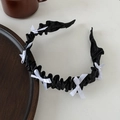 Serre-tête plissé Lolita noir avec nœuds en soie blanche sur une table beige - Nœud à Volants Noir