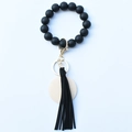 Detail showing matte black silicone beaded wristlet with gold clasp and leather tassel - Black