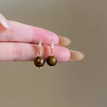 Detailed view of gold earrings with small zircons and a tiger eye stone pendant - 18# Three Rhinestones Gold Spherical Pendant (18# Silver Earring Post - Gold - Coffee)