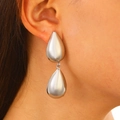 Fashionable double teardrop stud earrings in metallic silver finish shown on model - Silver Double Drop