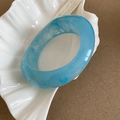 Detail of wide resin bangle with blue marble texture on a white shell plate - Sky Blue Cloud Texture Style