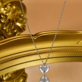 Dettaglio del ciondolo a cuore argento perlato appeso a una cornice dorata vintage - Pendente con Perla a Cuore Argento