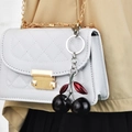 White quilted crossbody bag with golden chain strap and unique black cherry charm - Black Cherry