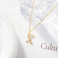 Macro view of gold letter K necklace pendant with micro-inset zircon and shiny finish - Letter X