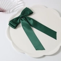 Barrette à nœud en satin vert foncé avec rubans sur une assiette décorative blanche - vert foncé