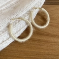 Detail of cream yarn-wrapped hoop earring on textured knit and wooden background - Off White