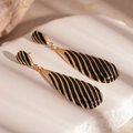 Macro view of vintage black enamel teardrop earrings with elegant golden zebra stripes - Black Drip Oil Drop Style (Silver Needle)
