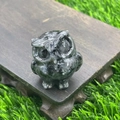 Speckled dark natural stone owl figurine on wood base with garden grass background - Larvikite