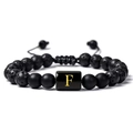 Gros plan du bracelet réglable en pierre de lave avec une lettre F dorée sur une perle noire - Lettre F(F)