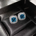 Close-up of luxury flower earrings with square blue topaz and white diamond halo in a box - Sea Blue Zirconia Stud Earrings (Pair)