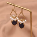 Golden drop earrings with white pearls and a deep blue gemstone on a display stand - Lapis Lazuli Pendant Style