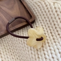 Detailaufnahme eines gelben Harzblumen-Haargummis auf einem braunen elastischen Band - Milchweiß