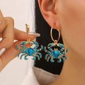Detail of blue enamel crab dangle earring worn by a model with golden hoop base - Blue Crab Earrings (12374)