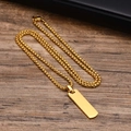 Dettaglio di una collana con ciondolo rettangolare dorato e catena grossa su legno - Pendente + Catena da 60cm / Oro