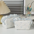Close-up of quilted makeup bag with blue bow patterns and decorative ruffle edges - Large / Blue