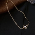 Collana dorata minimalista con ciondolo a fiore e perla su sfondo di tessuto scuro - Collana / Oro
